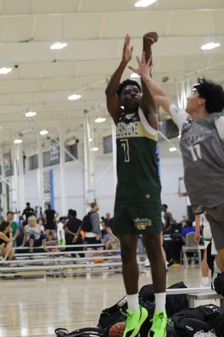 Basketball player shooting over defender indoors.