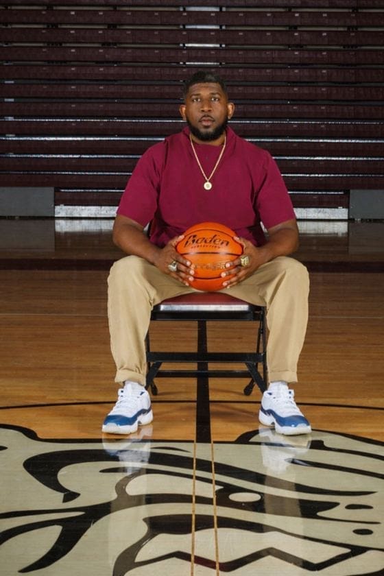 Man sitting on chair holding basketball indoors.