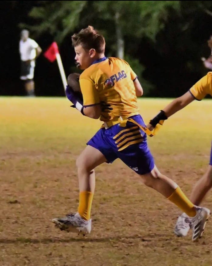 Youth flag football player running with ball.