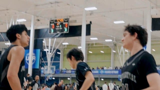 Three basketball players walking on indoor court