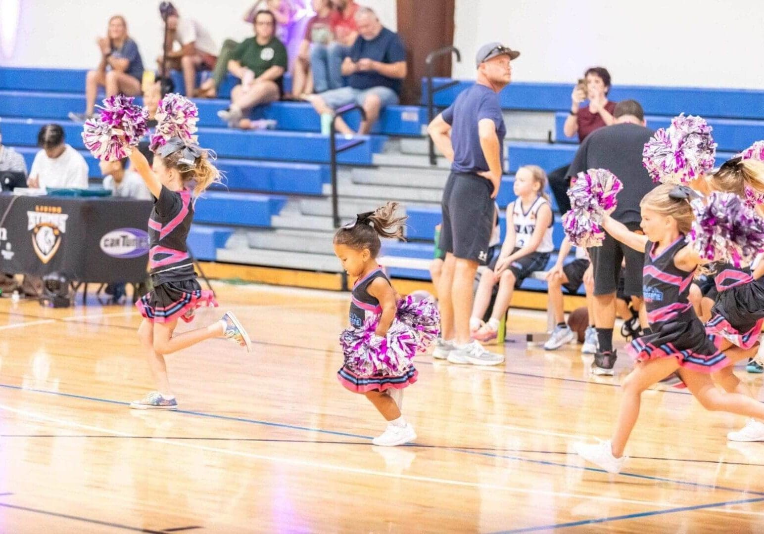 Young cheerleaders performing with purple pom-poms